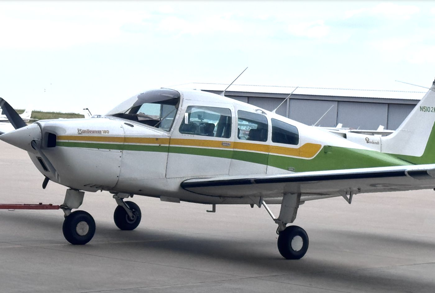 White Piper Cherokee with a green stripe parked on the ramp