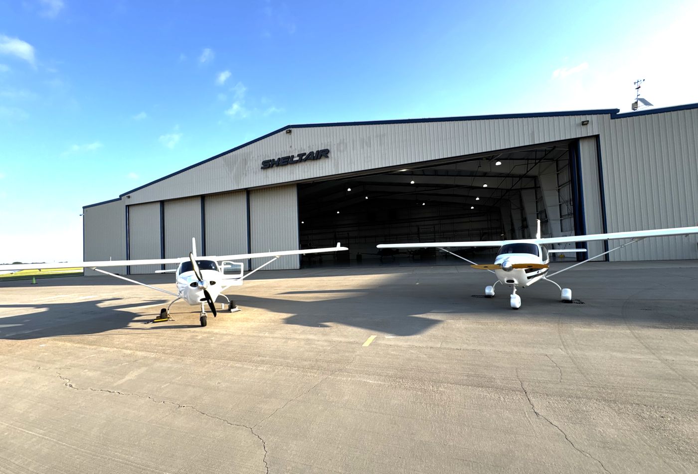 Two Jabiru J170s parked side by side outside the Sheltair hangars